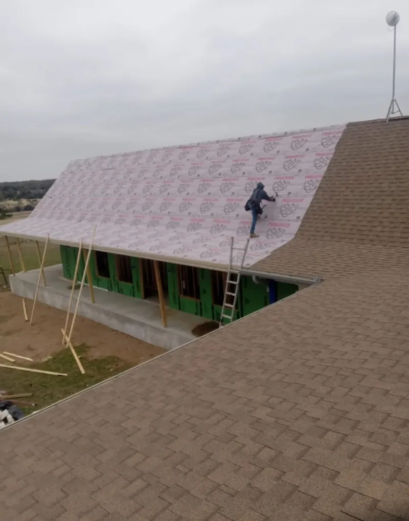 Worker preparing underlayment for a metal roof installation in Layhill